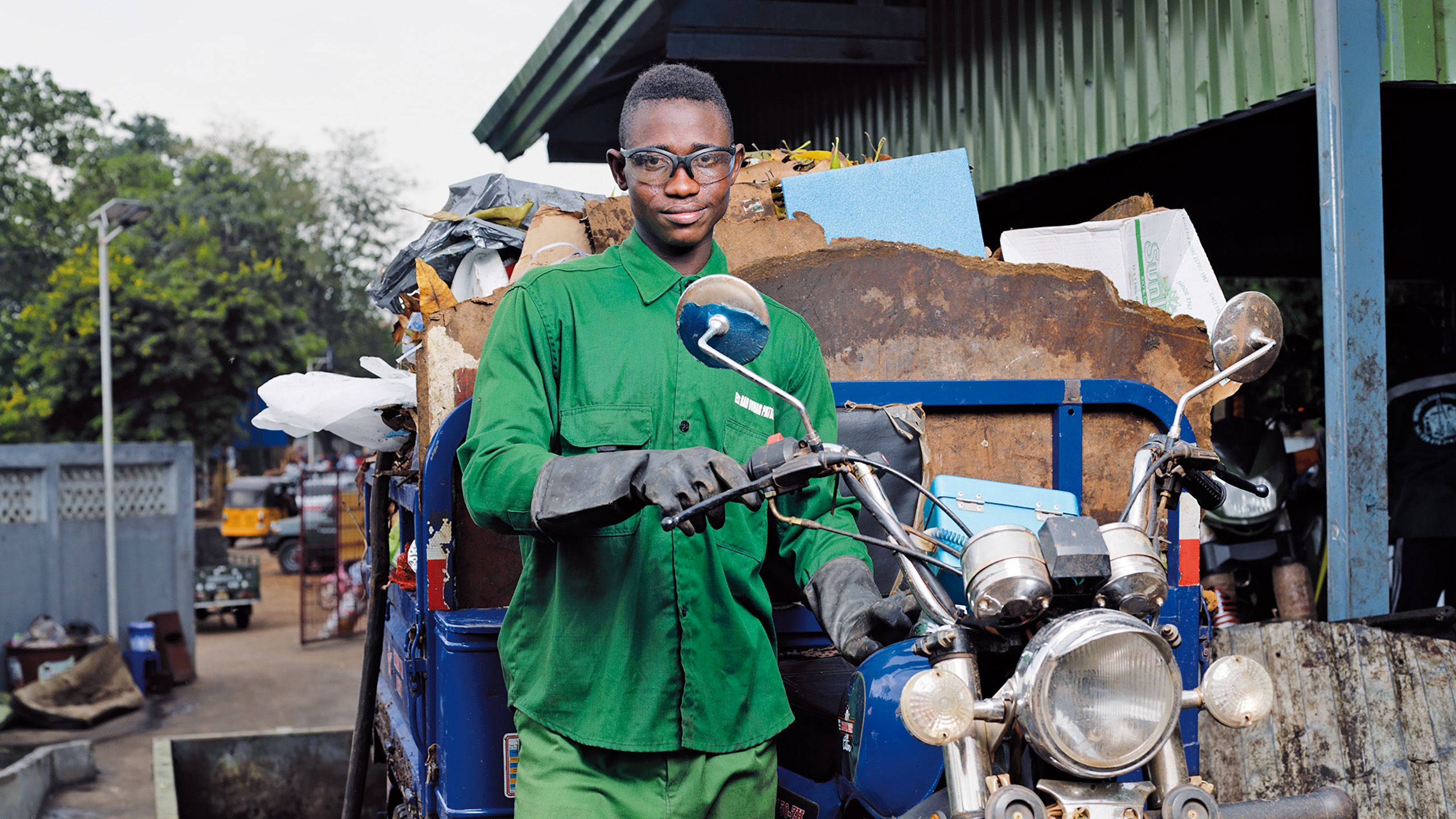 Young Guinean man standing next to a small motorised waste bike
