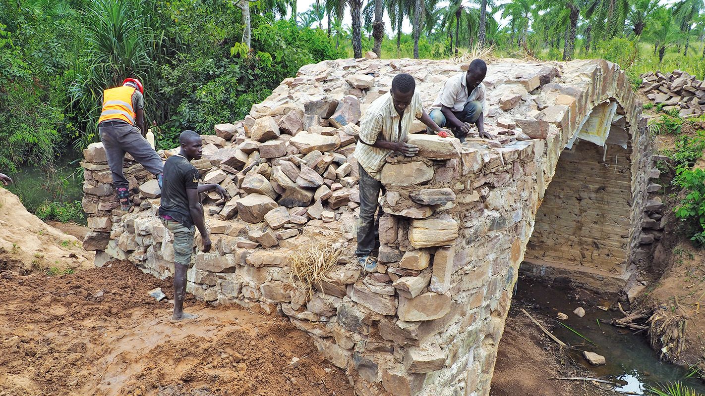 Workers building a stone arch bridge