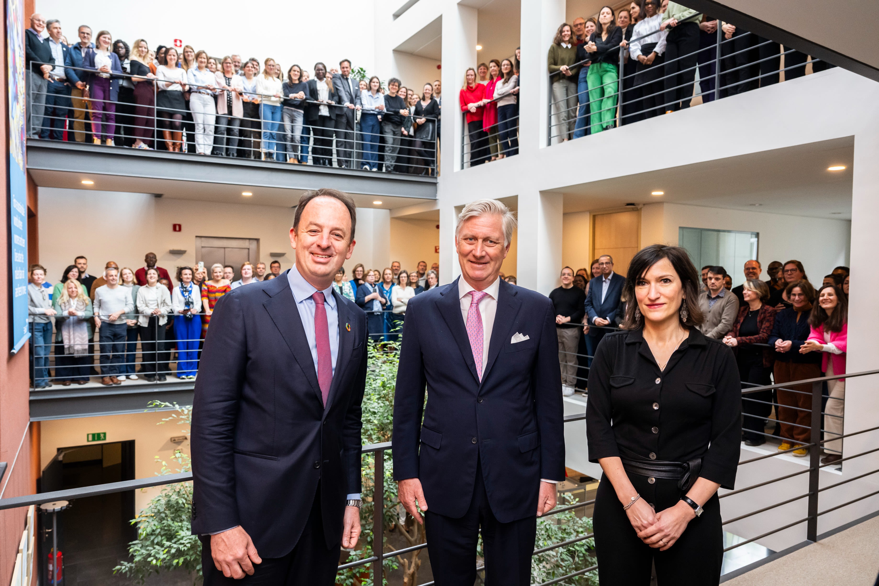 King Philippe of Belgium with a woman and a man and a group of people in the background