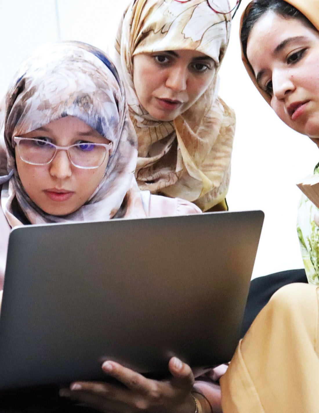 Three veiled women staring at a computer screen