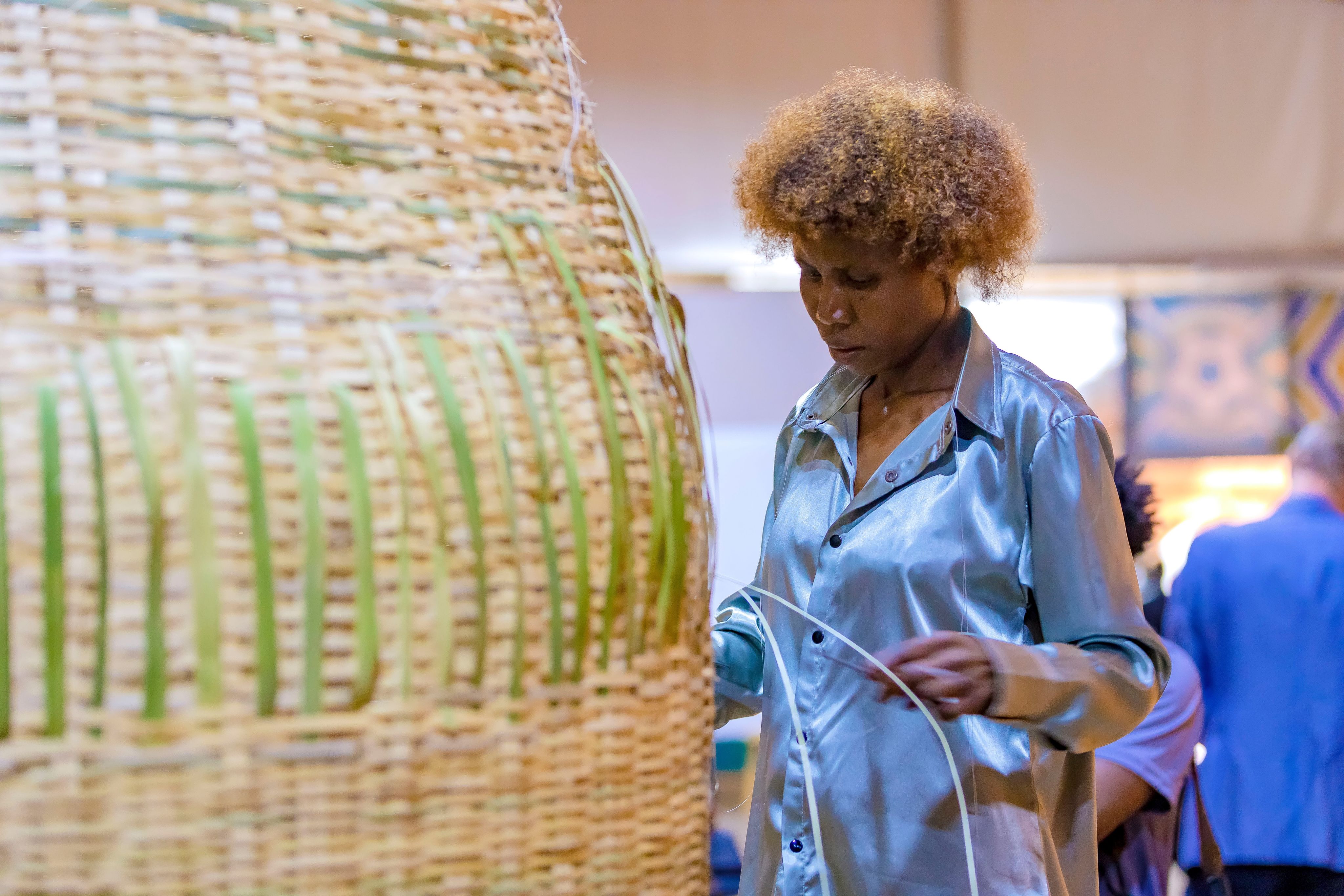 A Rwandan artist weaves a basket at the Awa Prize cereony in Kigali, 2023.